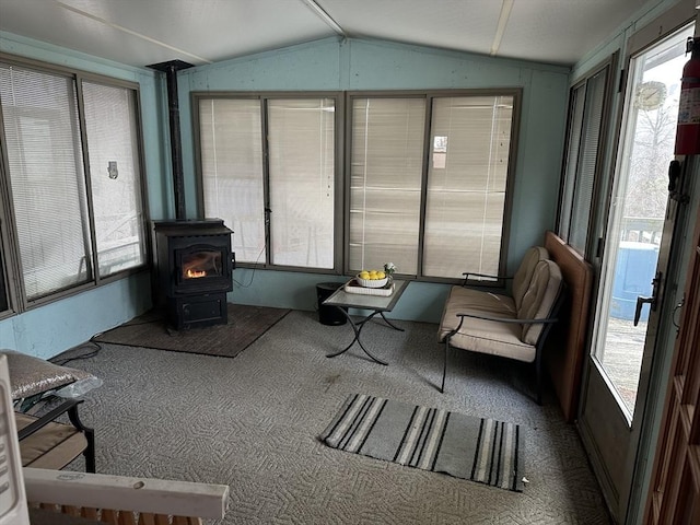 sunroom featuring plenty of natural light, lofted ceiling, and a wood stove