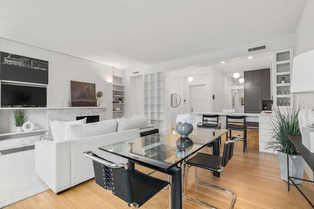 dining area with light wood-type flooring and built in features