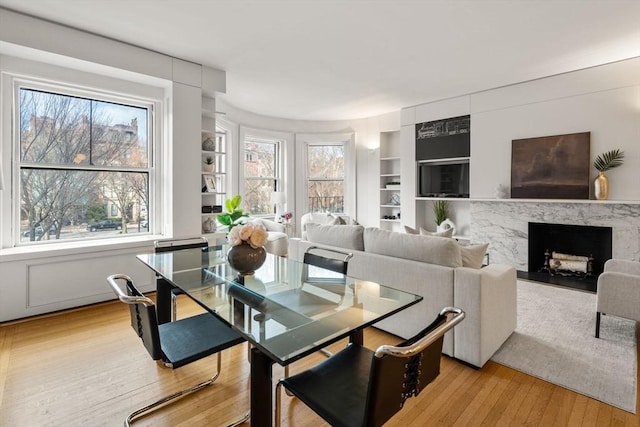 dining area featuring light hardwood / wood-style floors, a premium fireplace, and built in features