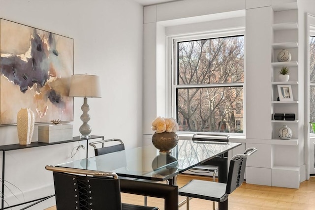 dining room with built in shelves and wood-type flooring