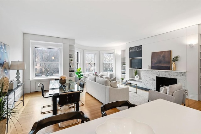 living room featuring light hardwood / wood-style floors, a high end fireplace, and built in shelves