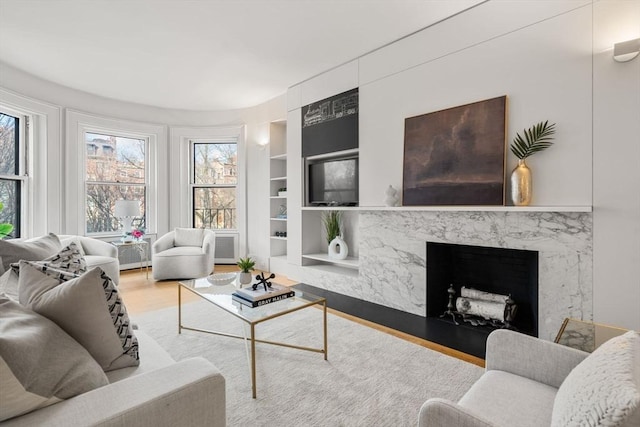 living room featuring light wood-type flooring, built in shelves, and a fireplace