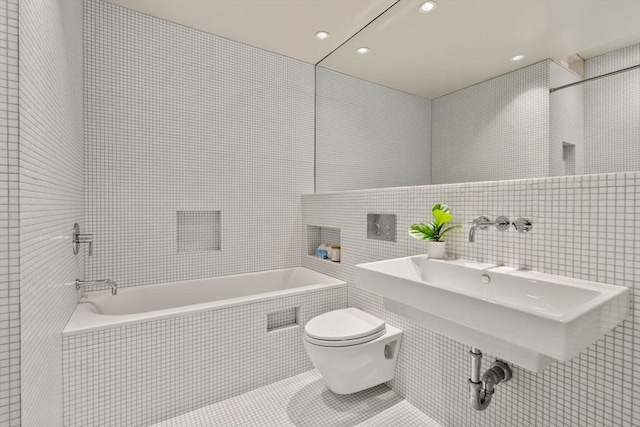 bathroom featuring tile walls, a tub, tile patterned floors, and toilet