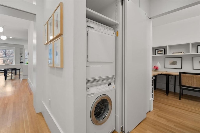 laundry area featuring stacked washer and dryer and light hardwood / wood-style flooring