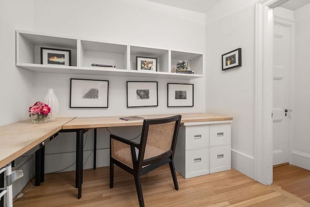 home office featuring built in desk and light hardwood / wood-style flooring