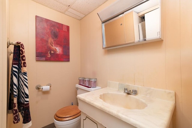 bathroom with a paneled ceiling, toilet, and vanity