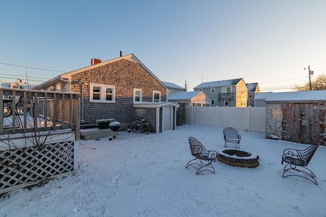 snow covered house with an outdoor fire pit and a shed