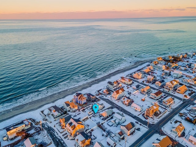 aerial view at dusk with a water view and a view of the beach