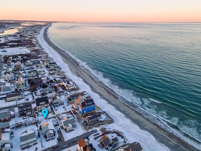 aerial view at dusk featuring a water view and a view of the beach