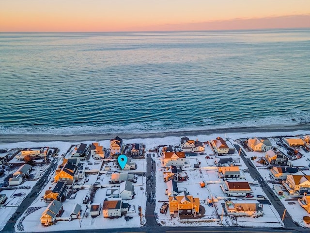 aerial view at dusk featuring a water view and a view of the beach