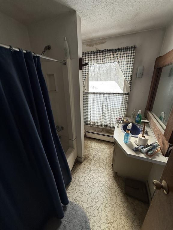 bathroom featuring a textured ceiling, a baseboard radiator, and vanity