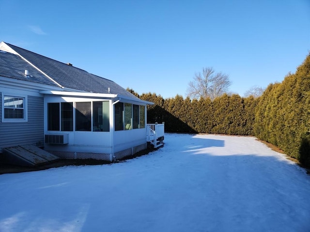 yard layered in snow featuring a sunroom