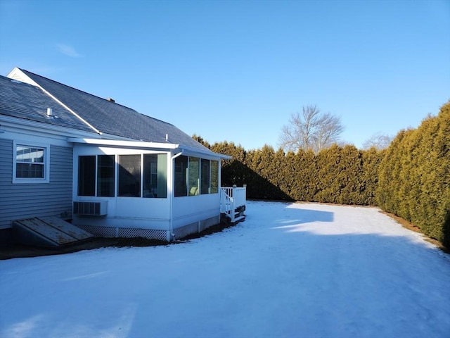 yard covered in snow featuring a sunroom