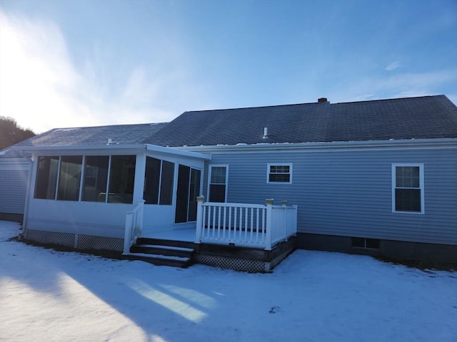 snow covered rear of property featuring a wooden deck and a sunroom