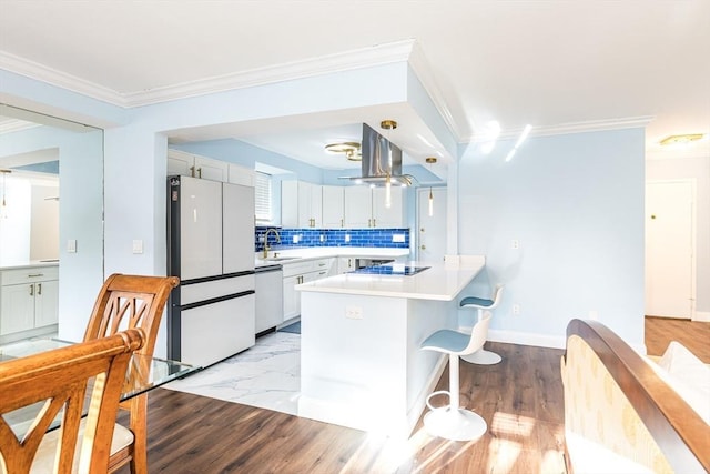 kitchen with tasteful backsplash, white appliances, island range hood, crown molding, and white cabinetry