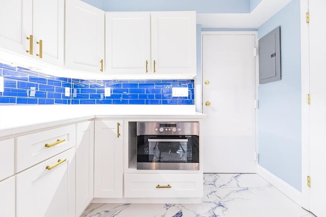 kitchen featuring decorative backsplash, stainless steel oven, white cabinetry, and electric panel