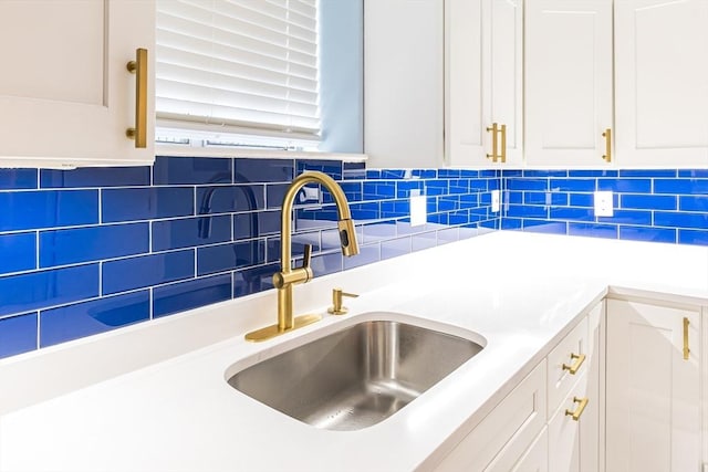 room details featuring tasteful backsplash, white cabinetry, and sink