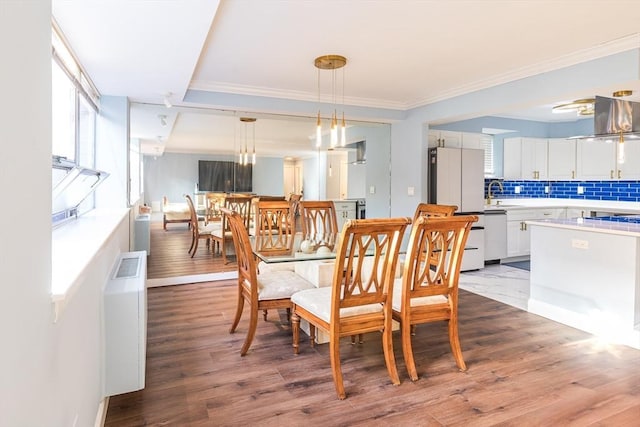 dining area with hardwood / wood-style flooring, ornamental molding, and sink