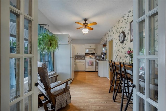 14 Cottage St, Whitman, MA 02382 - kitchen featuring white appliances, light wood-style flooring, wallpapered walls, white cabinets, and plenty of natural light