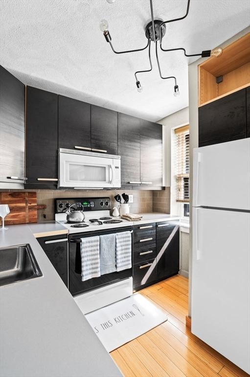 34 Beacon St Unit 3, Chelsea, MA 02150 - kitchen featuring white appliances, dark cabinets, light countertops, and decorative backsplash