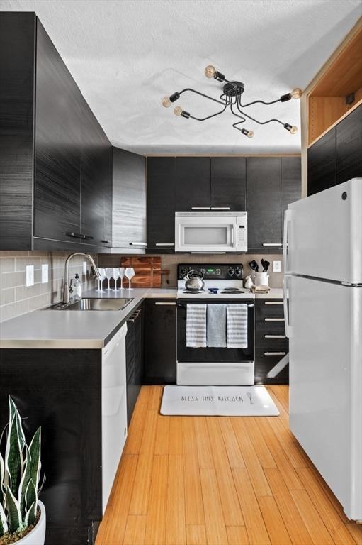 34 Beacon St Unit 3, Chelsea, MA 02150 - kitchen featuring white appliances, dark cabinets, modern cabinets, backsplash, and light countertops
