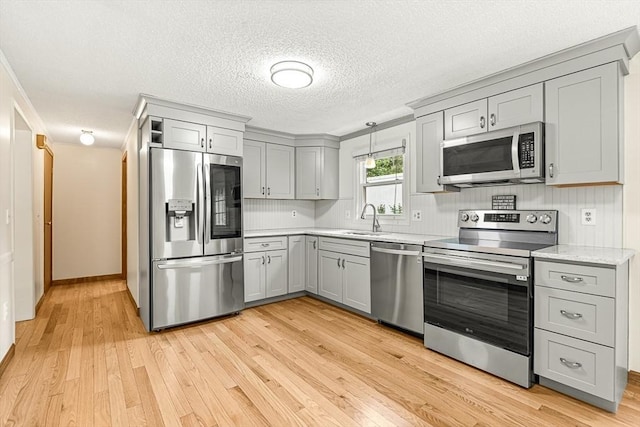 191 Franklin St Unit A, Stoneham, MA 02180 - kitchen featuring appliances with stainless steel finishes, gray cabinetry, a sink, light wood-type flooring, and a textured ceiling
