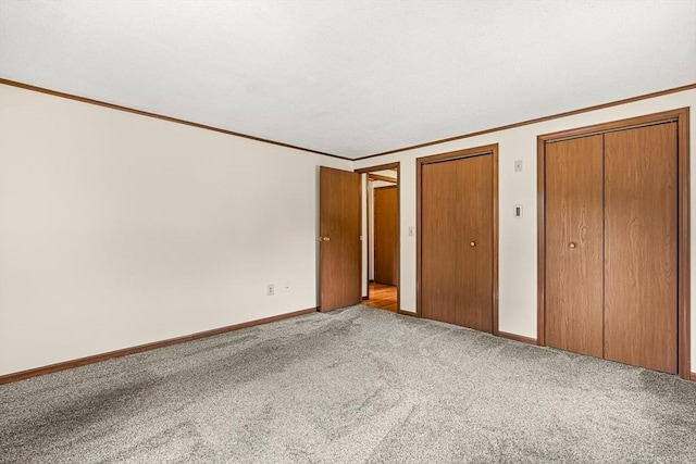 191 Franklin St Unit A, Stoneham, MA 02180 - unfurnished bedroom with two closets, crown molding, carpet, and baseboards