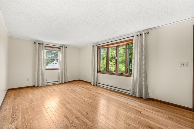 191 Franklin St Unit A, Stoneham, MA 02180 - unfurnished room featuring a baseboard heating unit, light wood finished floors, a textured ceiling, and baseboards