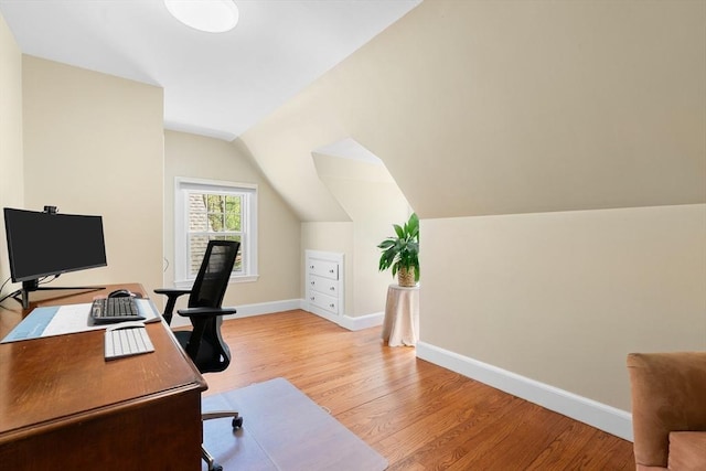 office featuring baseboards, light wood-style floors, and vaulted ceiling