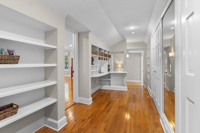 corridor with baseboards, built in features, and hardwood / wood-style floors
