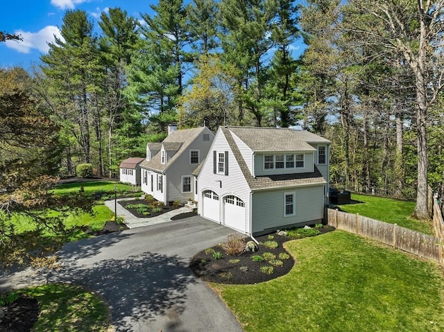 view of side of home featuring fence, an attached garage, a chimney, a lawn, and driveway