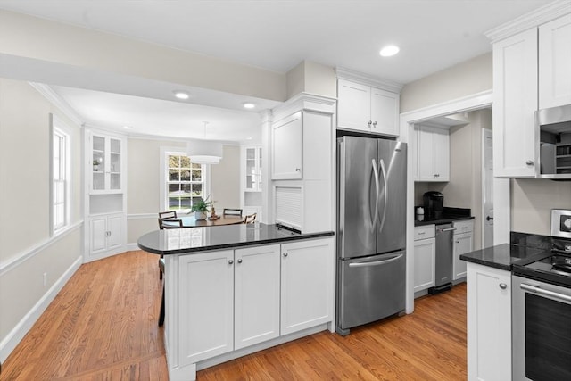 kitchen with light wood-type flooring, a peninsula, appliances with stainless steel finishes, and white cabinets