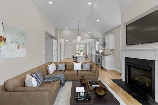 47 Spring St, Rehoboth, MA 02769 - living area with lofted ceiling, light wood finished floors, a glass covered fireplace, and recessed lighting