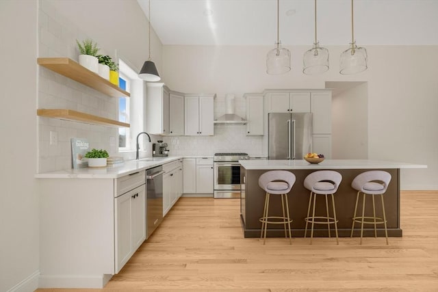 47 Spring St, Rehoboth, MA 02769 - kitchen featuring stainless steel appliances, wall chimney range hood, a breakfast bar, a kitchen island, and light wood-style flooring