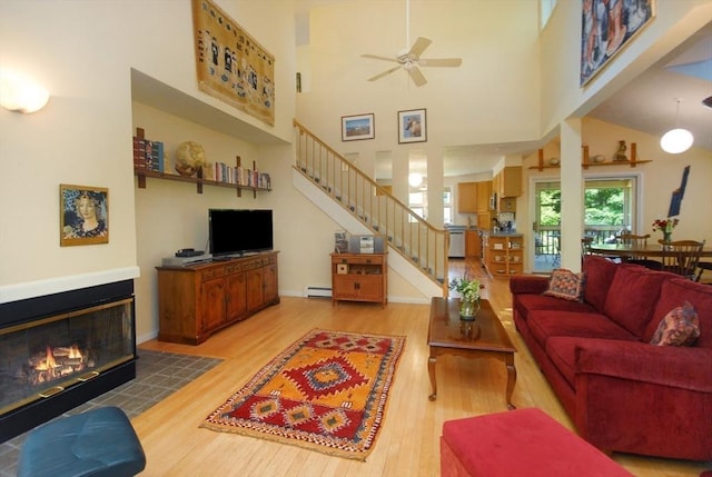 4 Half Moon Hl Unit 4, Acton, MA 01720 - living area featuring light wood-style flooring, stairway, a baseboard heating unit, a glass covered fireplace, and a high ceiling