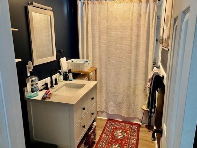 bathroom featuring hardwood / wood-style flooring, shower / tub combo with curtain, and vanity