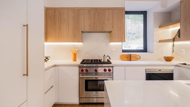 kitchen with white cabinetry, premium stove, oven, decorative backsplash, and light stone countertops