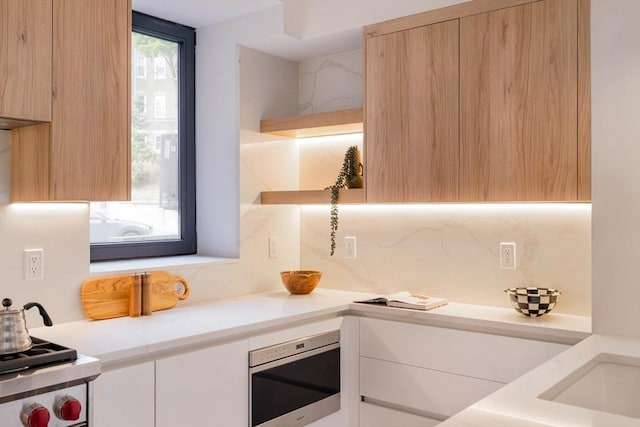 kitchen featuring white cabinetry, stainless steel microwave, light brown cabinetry, and decorative backsplash