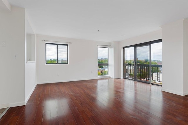 spare room featuring dark hardwood / wood-style flooring and a healthy amount of sunlight