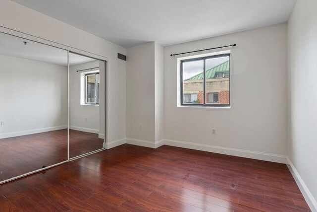 unfurnished bedroom with a closet and dark wood-type flooring