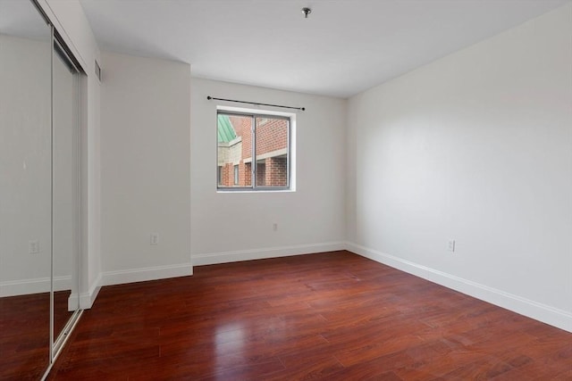 unfurnished bedroom featuring dark wood-type flooring and a closet