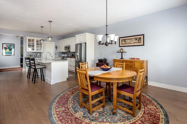 dining area with dark hardwood / wood-style floors, sink, and an inviting chandelier