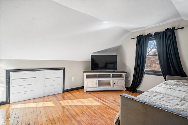 bedroom featuring vaulted ceiling, light wood-style floors, and baseboards
