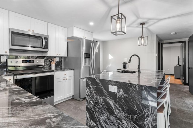 kitchen with appliances with stainless steel finishes, a sink, dark stone counters, white cabinets, and recessed lighting