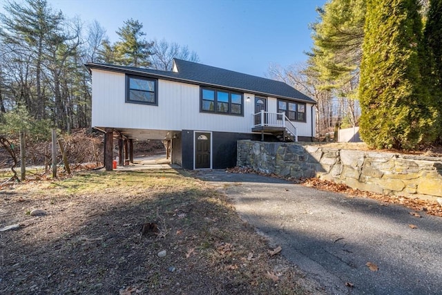 view of front of house with a carport, driveway, and roof with shingles