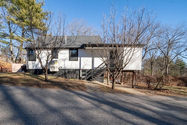 view of side of home featuring stairway and a shingled roof
