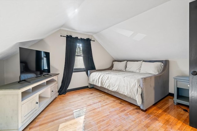 bedroom with light wood-type flooring and lofted ceiling