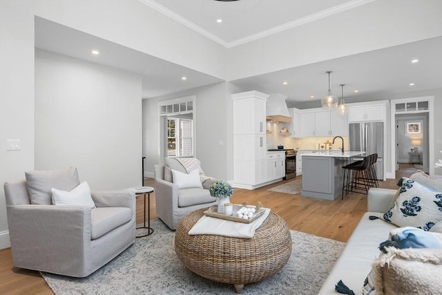 living room featuring ornamental molding, light wood-type flooring, baseboards, and recessed lighting