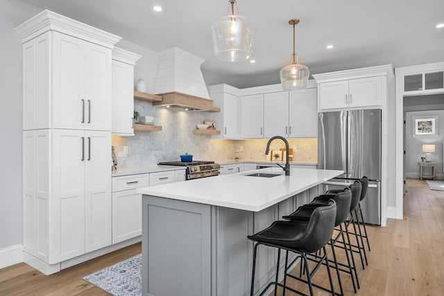 kitchen featuring premium range hood, light countertops, appliances with stainless steel finishes, and a sink