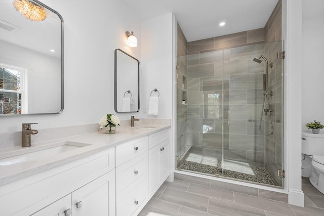 full bathroom featuring toilet, a stall shower, double vanity, and a sink